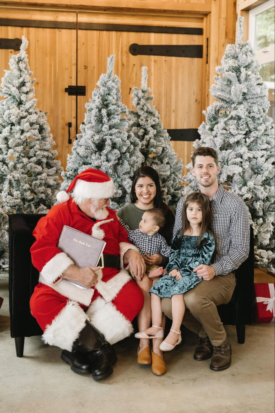Holiday family portrait with Santa in front of Christmas trees