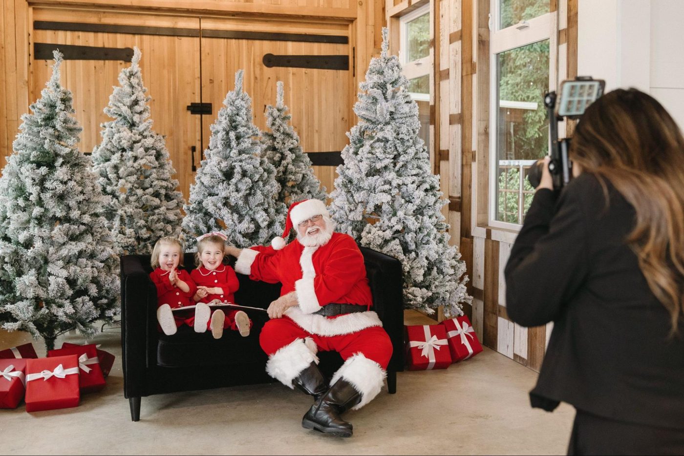 Family taking photos with Santa beside snowy Christmas trees