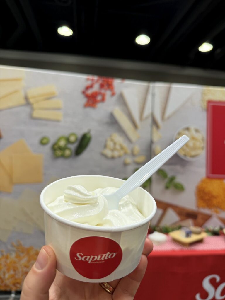 Guest holding a Saputo branded cup of soft serve at a trade show booth